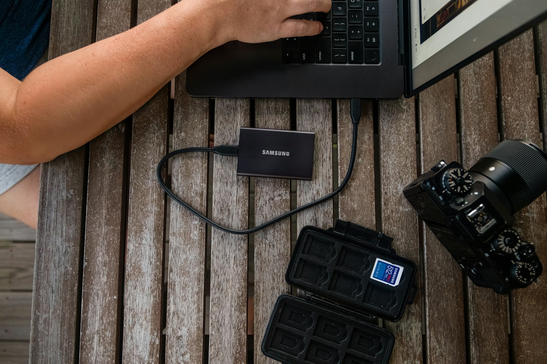 Портативный SSD рядом с ноутбуком, камерой и картой памяти